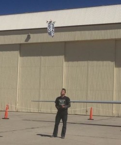 Sam Yergler standing next to a Predator drone and flying his "peace drone"
